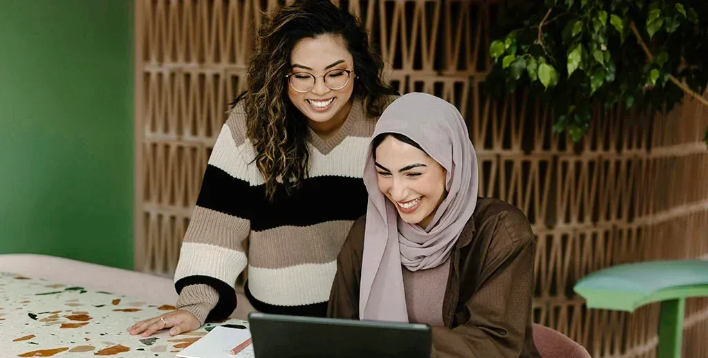 smiling coworkers sharing laptop